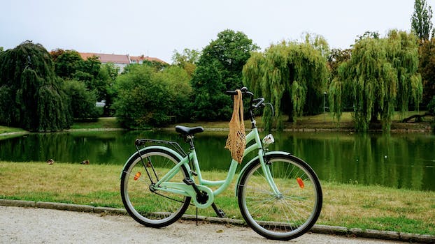 Green City Bike Parked on a Pathway Next to a Pond 