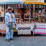 Man in Traditional Clothing in Front of a Market Stall