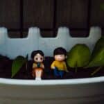 Small figurines in flowerpot with plant