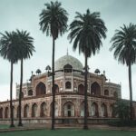 Low angle of beautiful well maintained garden with palms and ancient building of Humayun s Tomb located in Delhi