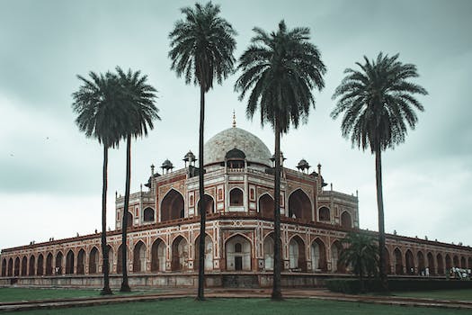 Low angle of beautiful well maintained garden with palms and ancient building of Humayun s Tomb located in Delhi