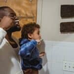 Black father and son brushing teeth during morning procedure