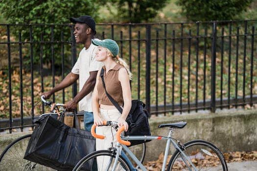 Food Delivery Man and Woman on Bicycles Carrying Food Delivery Bags Talking