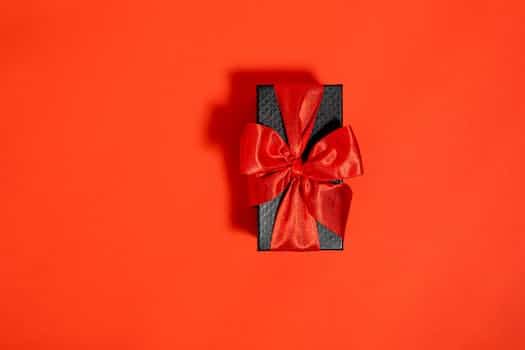A Black Box Tied With Red Ribbon on Red Background