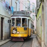 Famous old fashioned number 28 Lisbon tram in narrow street of Lisbon with shabby buildings