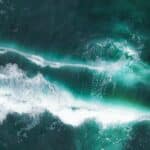From above of turquoise water of ocean with white foam and waves in summer