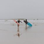 Photography of People On Seashore Holding Surboard