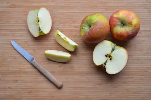 Slices of ripe apples and knife on wooden surface