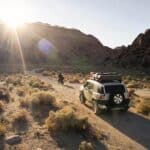 Breathtaking landscape with rocky hills and dry vegetation against sundown and car with motorbike on narrow dusty road