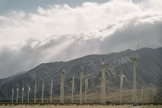 Wind Turbines Near Mountains Under A Cloudy Sky