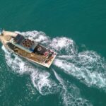 Drone view of boat with open deck and fishing equipment floating on calm sea at daytime